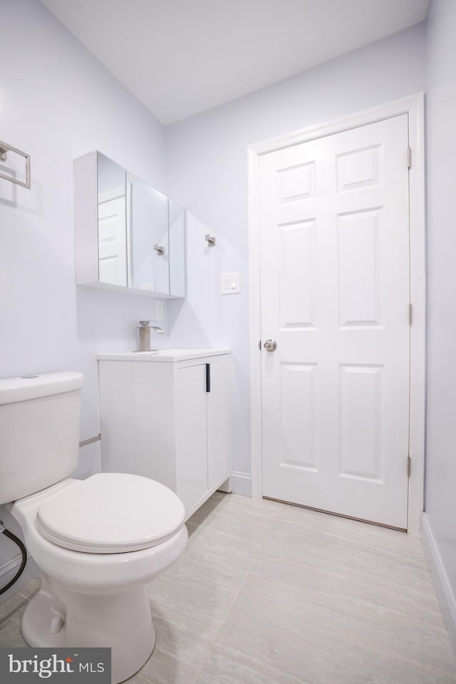 bathroom with vanity, baseboards, and toilet