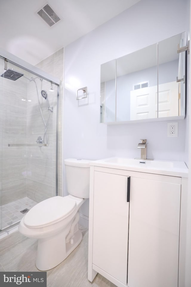 full bath featuring vanity, a shower stall, toilet, and visible vents