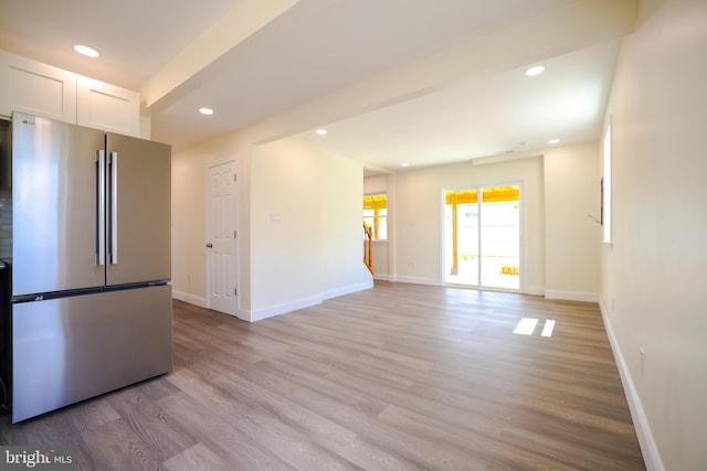kitchen with light wood-type flooring, freestanding refrigerator, white cabinetry, and baseboards
