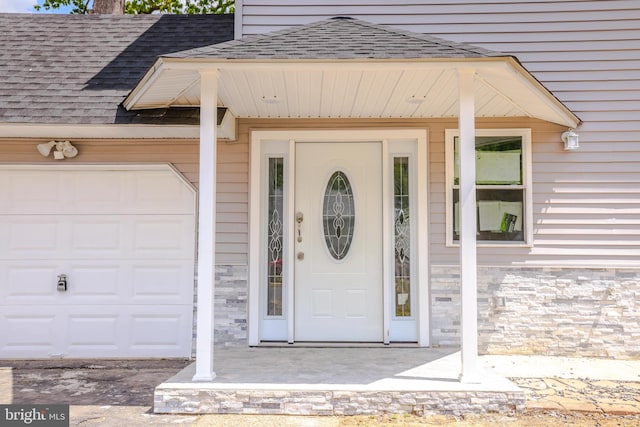 property entrance with a chimney, a shingled roof, stone siding, and a garage