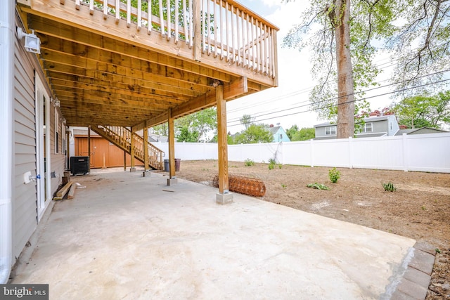 view of patio / terrace featuring a fenced backyard, a deck, central AC, and stairway