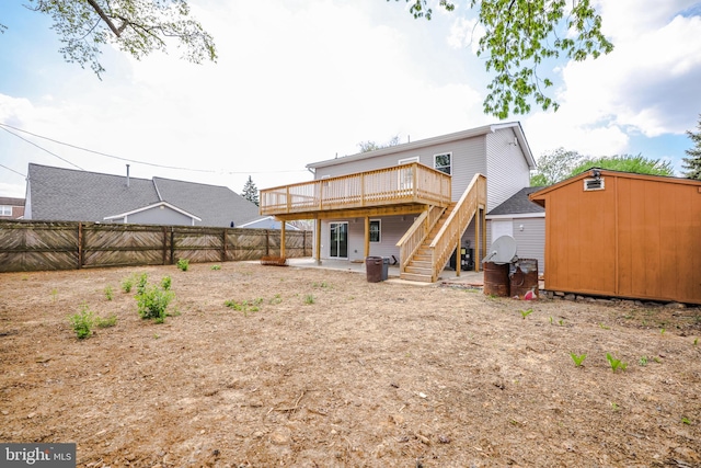 back of property with an outdoor structure, a wooden deck, a fenced backyard, a storage shed, and stairway