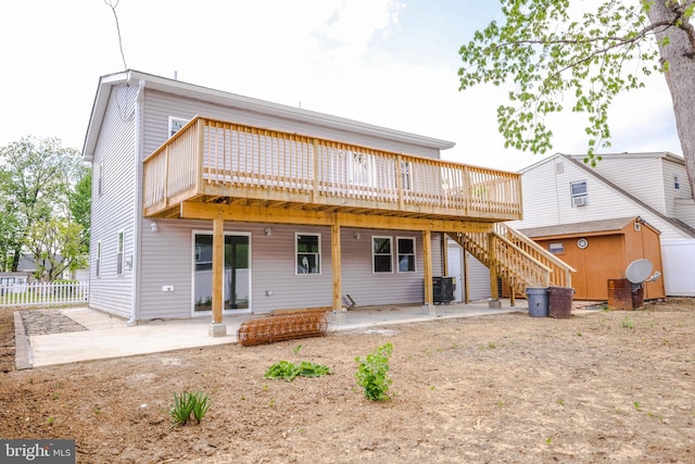back of house featuring a patio, a wooden deck, an outbuilding, and a shed