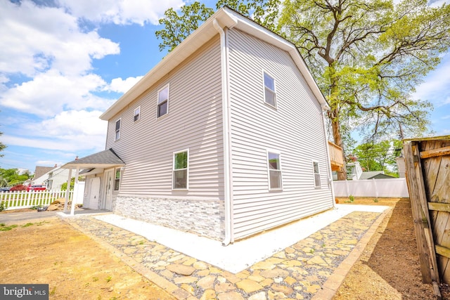 view of property exterior featuring fence and stone siding
