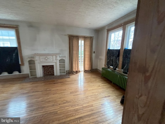 3314 Egerton Rd, Baltimore, MD 21215 - unfurnished living room featuring light wood-style floors, radiator, plenty of natural light, and a textured ceiling