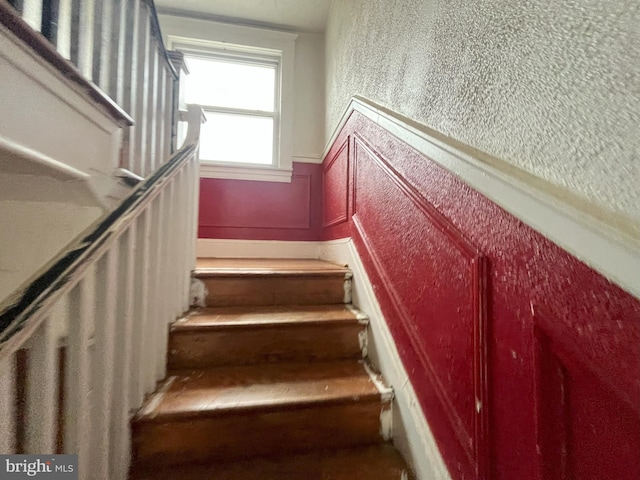 3314 Egerton Rd, Baltimore, MD 21215 - stairway featuring a textured wall, a wainscoted wall, and a decorative wall