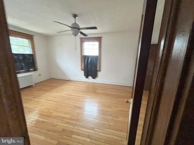 3314 Egerton Rd, Baltimore, MD 21215 - unfurnished room with light wood-type flooring, baseboards, ceiling fan, and radiator heating unit