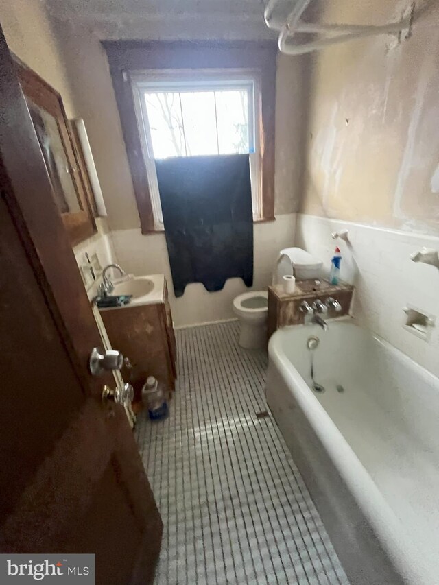 3314 Egerton Rd, Baltimore, MD 21215 - full bath featuring vanity, tile patterned flooring, toilet, and a tub to relax in