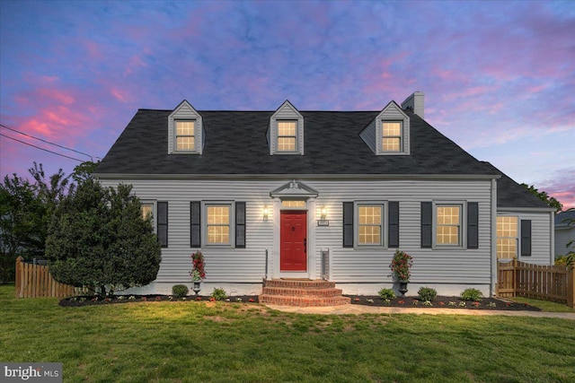 cape cod-style house featuring a chimney, a shingled roof, fence, and a front yard