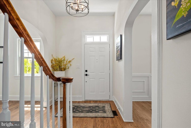 entrance foyer with a healthy amount of sunlight, arched walkways, and wood finished floors