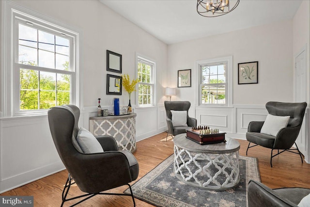 sitting room featuring a chandelier, wood finished floors, and a wainscoted wall