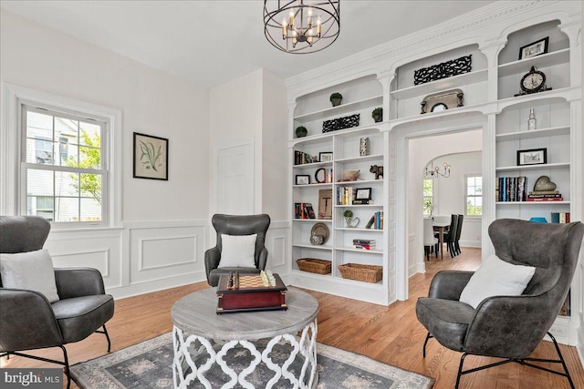 sitting room featuring a notable chandelier, wood finished floors, and a wainscoted wall