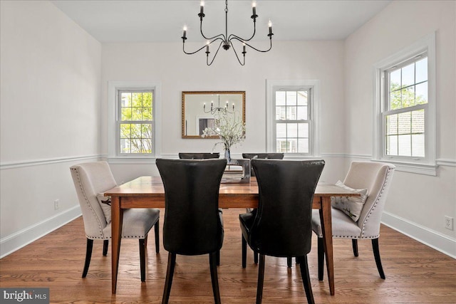dining area with a chandelier, a wealth of natural light, and wood finished floors