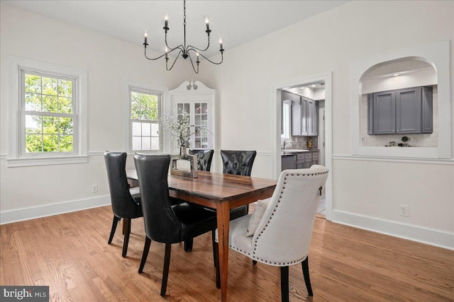 dining room with baseboards, a chandelier, and light wood finished floors