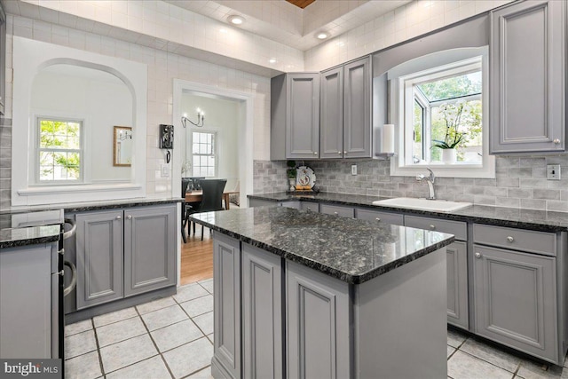 kitchen featuring plenty of natural light, a sink, light tile patterned flooring, and gray cabinetry