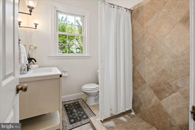 bathroom with vanity, baseboards, toilet, and tiled shower