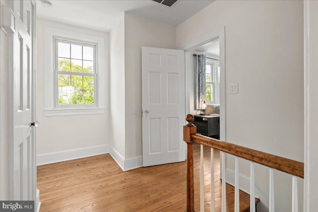 hall featuring light wood-style floors, baseboards, and visible vents