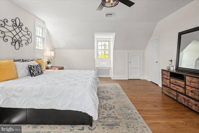 bedroom with visible vents, lofted ceiling, multiple windows, and wood finished floors