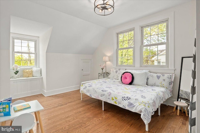 bedroom with baseboards, multiple windows, vaulted ceiling, and light wood-style flooring