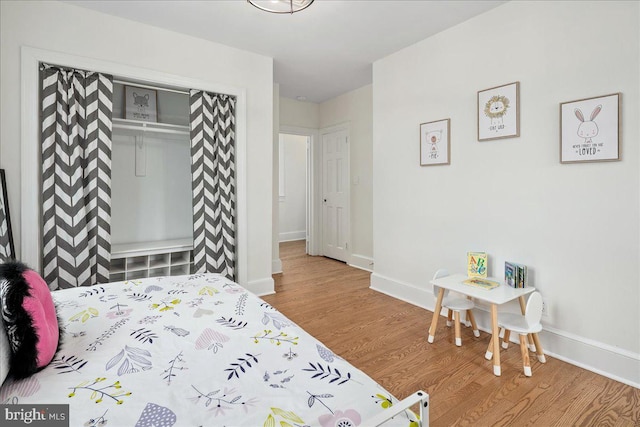 bedroom featuring baseboards, wood finished floors, and a closet