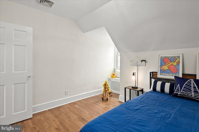 bedroom with baseboards, visible vents, wood finished floors, and lofted ceiling