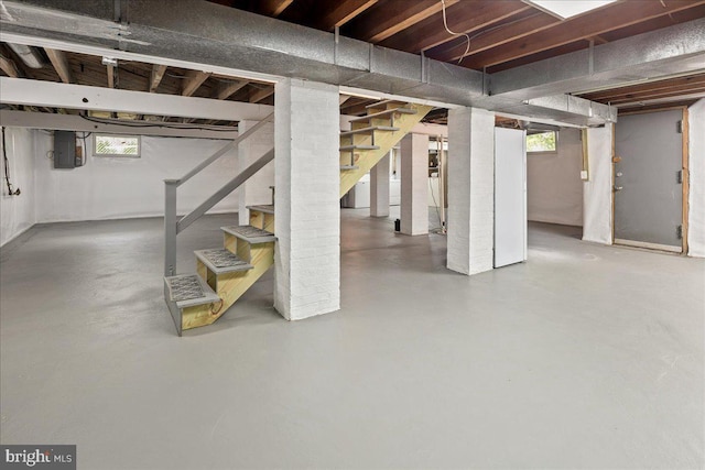 basement with stairs, a healthy amount of sunlight, and electric panel