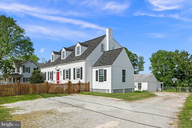 view of front facade featuring a shingled roof, a fenced front yard, and driveway