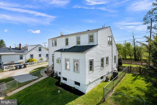 back of house featuring a yard, central AC, a chimney, and a fenced backyard
