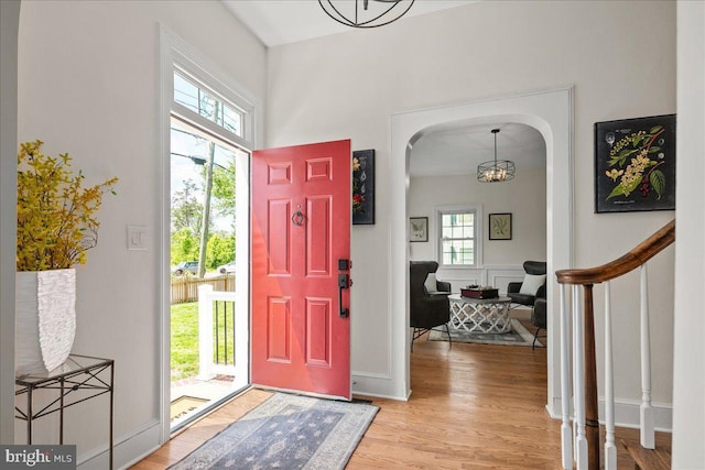 entryway with light wood-type flooring, arched walkways, a notable chandelier, and stairway