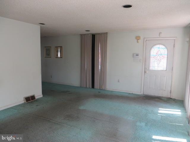 entrance foyer featuring a textured ceiling, visible vents, and carpet floors