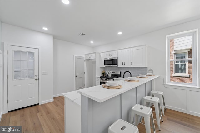 25 N Brown St, Gloucester City, NJ 08030 - kitchen featuring appliances with stainless steel finishes, light wood-style flooring, a breakfast bar area, backsplash, and white cabinetry