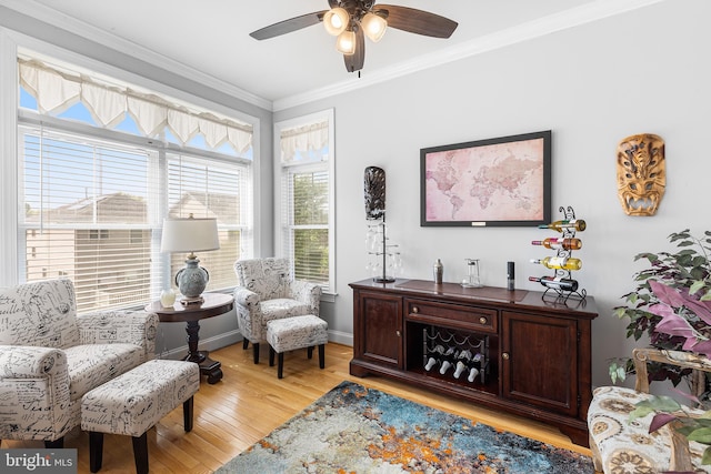 sitting room with crown molding, light wood-style flooring, a ceiling fan, and baseboards