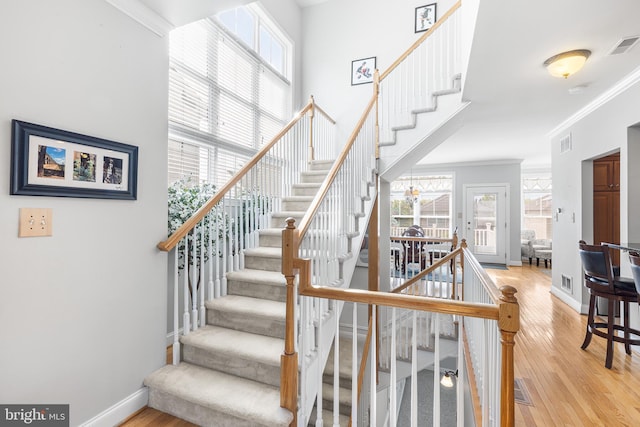 staircase featuring crown molding, wood finished floors, and baseboards