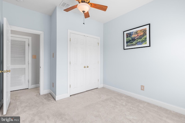 unfurnished bedroom featuring light carpet, a closet, baseboards, and ceiling fan