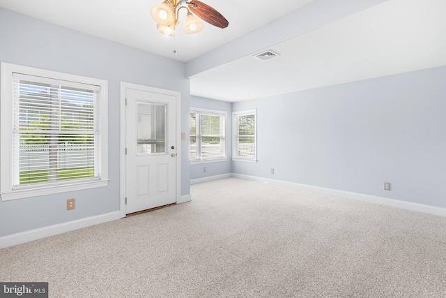 carpeted spare room featuring baseboards and a ceiling fan