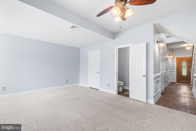 unfurnished bedroom with dark colored carpet, baseboards, and ensuite bathroom