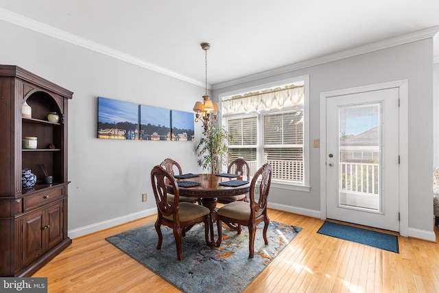 dining room featuring light wood finished floors, ornamental molding, and baseboards