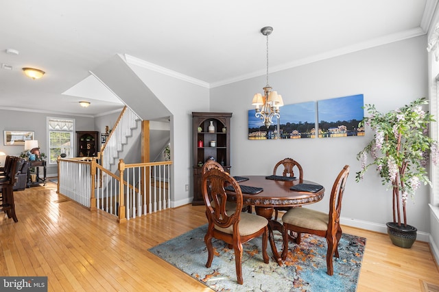 dining area with crown molding, wood-type flooring, a chandelier, baseboards, and stairway