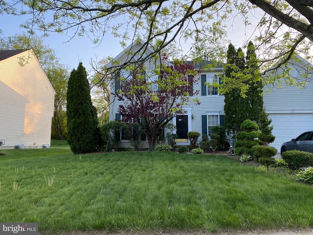 colonial home with a garage and a front yard