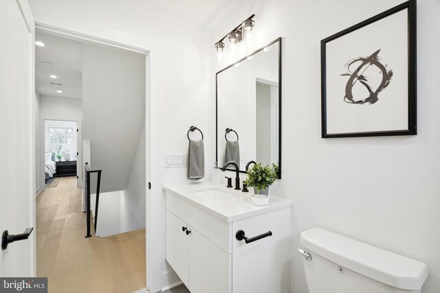 bathroom with vanity, wood finished floors, toilet, recessed lighting, and connected bathroom