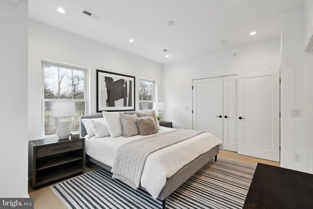 bedroom featuring visible vents, recessed lighting, light wood-style flooring, and a closet