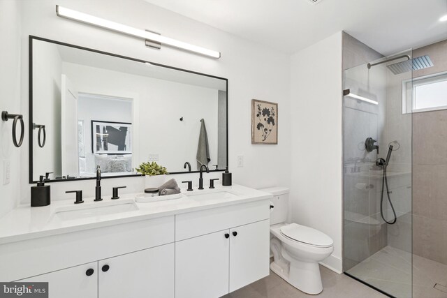 bathroom with double vanity, a sink, a walk in shower, and toilet
