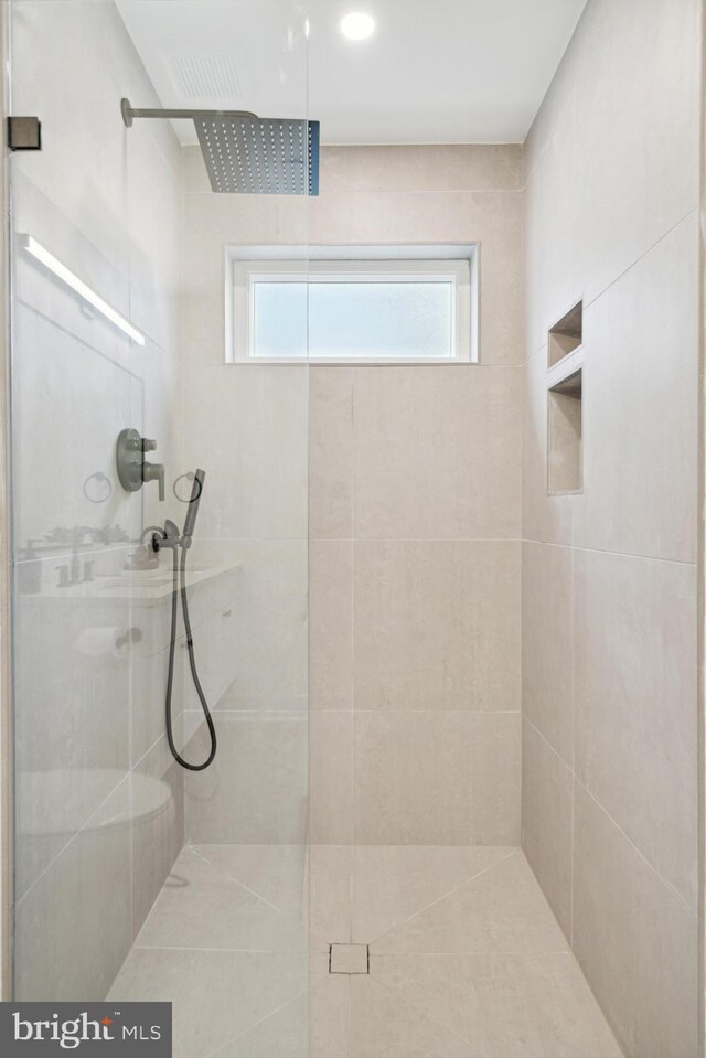 bathroom with a tile shower and plenty of natural light