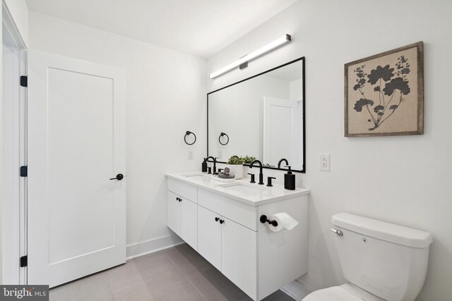 bathroom featuring double vanity, toilet, a sink, and tile patterned flooring