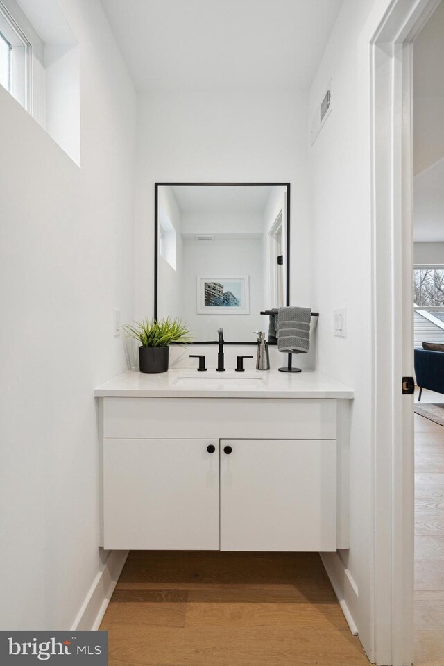 bathroom featuring vanity, baseboards, wood finished floors, and visible vents