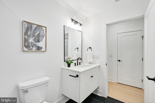 bathroom with toilet, wood finished floors, and vanity