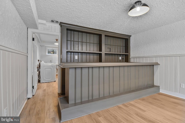6911 Wells Pkwy, University Park, MD 20782 - bar area featuring a textured ceiling, a textured wall, wood finished floors, and a wainscoted wall