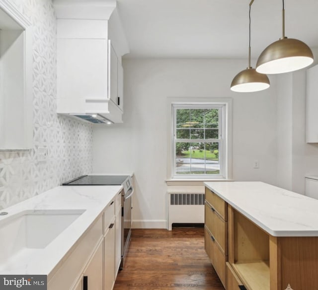 kitchen featuring pendant lighting, light stone countertops, stainless steel range with electric stovetop, dark wood-style floors, and radiator heating unit