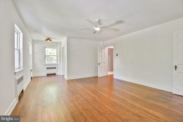 6911 Wells Pkwy, University Park, MD 20782 - unfurnished living room featuring radiator heating unit, ceiling fan, wood finished floors, and baseboards