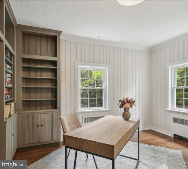 office with visible vents, wood finished floors, baseboards, radiator, and ornamental molding
